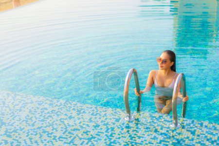 Téléchargez les photos : Portrait belle jeune femme asiatique relax sourire profiter des loisirs autour de la piscine en hôtel station balnéaire en vacances - en image libre de droit