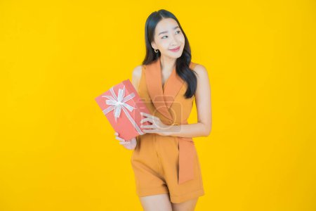 Foto de Retrato hermosa joven mujer asiática sonrisa con caja de regalo roja sobre fondo de color - Imagen libre de derechos