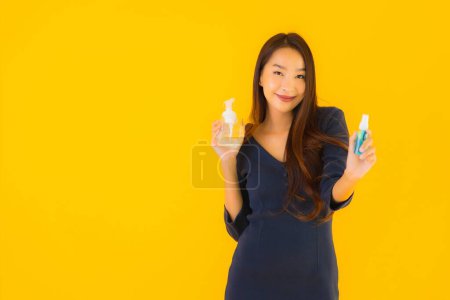 Photo for Portrait beautiful young asian woman with alcohol gel and spray for protect from coronavirus or covid19 on yellow isolated background - Royalty Free Image