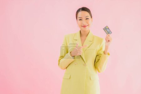 Téléchargez les photos : Portrait belle jeune femme d'affaires asiatique avec carte de crédit sur fond de couleur - en image libre de droit