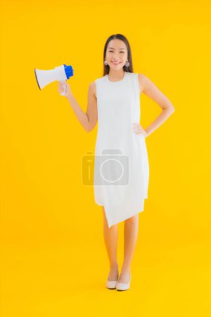 Photo for Portrait beautiful young asian woman with megaphone on yellow isolated background - Royalty Free Image