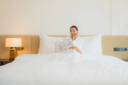 Téléchargez les photos : Portrait belle jeune asiatique femme relax sourire loisirs sur lit dans chambre intérieur - en image libre de droit