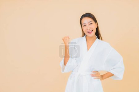 Téléchargez les photos : Portrait belle jeune femme asiatique porter peignoir avec sourire sur fond de couleur - en image libre de droit