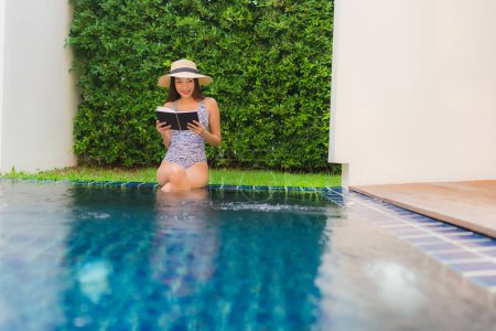 Foto de Retrato hermosa joven asiática mujer leer libro alrededor de piscina en hotel resort para vacaciones de viaje - Imagen libre de derechos
