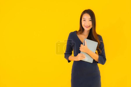 Foto de Retrato hermosa joven asiática mujer con inteligente tableta electrónica en amarillo aislado fondo - Imagen libre de derechos