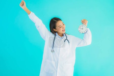 Photo for Portrait beautiful young asian doctor woman with clock or alarm on blue isolated background - Royalty Free Image