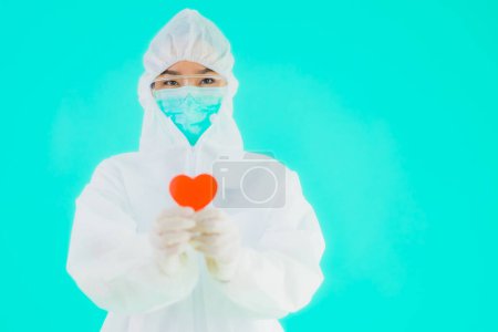 Foto de Retrato hermosa joven asiática médico mujer usar ppe o equipo de protección personal para proteger de coronavirus o covid19 mostrar el corazón en azul aislado fondo - Imagen libre de derechos