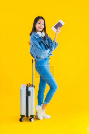 Téléchargez les photos : Portrait belle jeune femme asiatique voyage et loisirs avec sac à bagages et passeport, carte d'embarquement sur fond jaune isolé - en image libre de droit