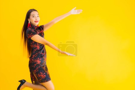 Foto de Retrato hermosa mujer asiática joven usar vestido chino con acción para el concepto de año nuevo chino sobre fondo aislado amarillo - Imagen libre de derechos