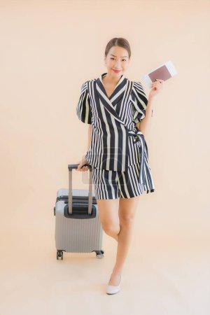 Photo for Portrait beautiful young asian woman with luggage bag passport and airplane ticket on brown background - Royalty Free Image