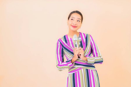 Photo for Portrait beautiful young asian woman with fork and spoon ready to eat on color background - Royalty Free Image