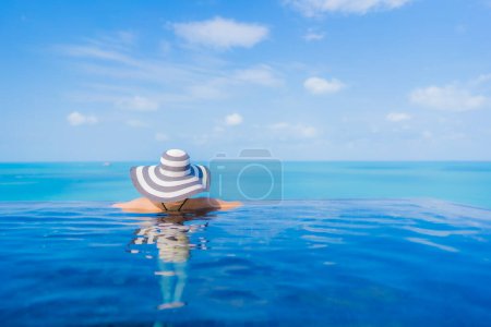 Téléchargez les photos : Portrait belle jeune femme asiatique relax sourire loisirs autour de la piscine extérieure en hôtel station balnéaire avec vue sur mer océan - en image libre de droit