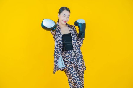 Téléchargez les photos : Portrait belle jeune femme asiatique avec gant de boxe sur fond de couleur - en image libre de droit