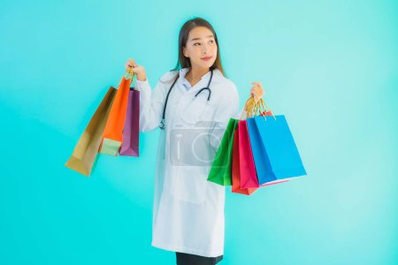 Photo for Portrait beautiful young asian doctor woman with colorful shopping bag from shopping mall on blue isolated background - Royalty Free Image