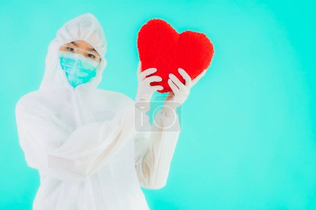 Foto de Retrato hermosa joven asiática médico mujer usar ppe o equipo de protección personal para proteger de coronavirus o covid19 mostrar el corazón en azul aislado fondo - Imagen libre de derechos