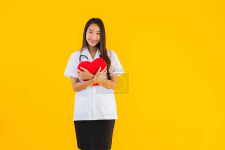 Photo for Portrait beautiful young asian doctor woman show heart for symbol of love on yellow isolated background - Royalty Free Image