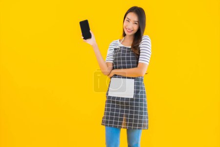 Photo for Portrait beautiful young asian woman use smart mobile phone on yellow isolated background - Royalty Free Image