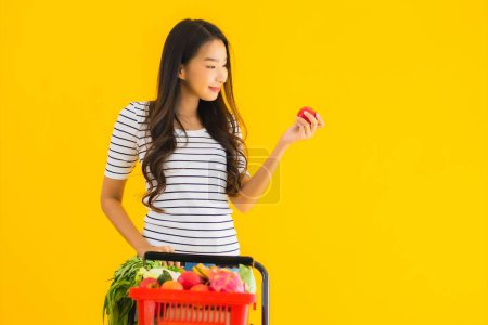 Photo for Portrait beautiful young asian woman shopping grocery from supermarket and cart on yellow isolated background - Royalty Free Image