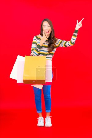 Photo for Portrait beautiful young asian woman with colorful shopping bag and credit card on red background - Royalty Free Image