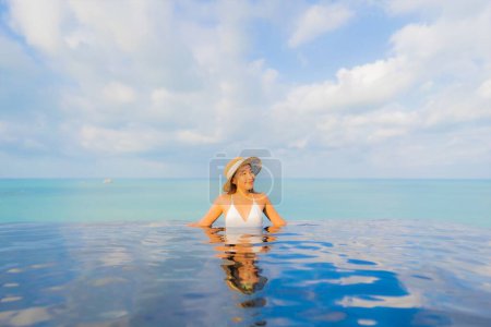 Téléchargez les photos : Portrait belle jeune femme asiatique relax sourire loisirs autour de la piscine extérieure dans la station hôtelière en vacances de voyage - en image libre de droit