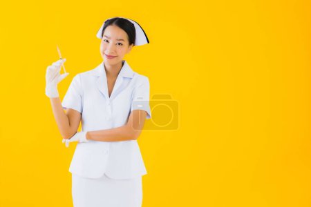 Foto de Retrato hermosa joven asiática mujer tailandesa enfermera usar guante en amarillo aislado fondo - Imagen libre de derechos