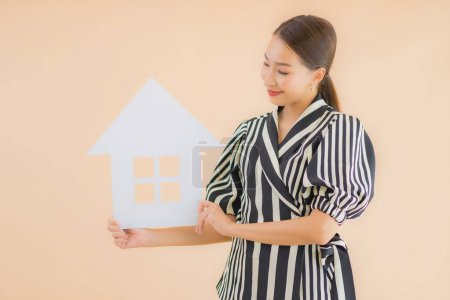 Foto de Retrato hermosa joven asiática mujer mostrar casa o casa papel cartel sobre fondo marrón - Imagen libre de derechos