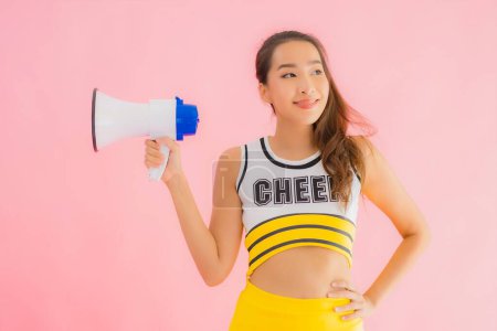 Photo for Portrait beautiful young asian woman cheerleader with megaphone on pink isolated background - Royalty Free Image