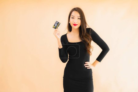 Téléchargez les photos : Portrait belle jeune femme asiatique avec carte de crédit pour faire du shopping sur fond isolé couleur - en image libre de droit