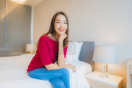 Foto de Retrato hermosa joven asiática mujer sonrisa relajarse en cama en dormitorio interior - Imagen libre de derechos