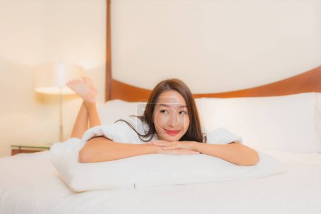 Téléchargez les photos : Portrait belle jeune femme asiatique sourire détendre loisirs sur lit dans chambre à coucher intérieur - en image libre de droit
