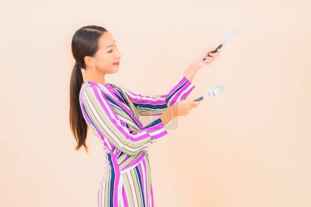 Foto de Retrato hermosa joven asiática mujer con tenedor y cuchara listo para comer en color de fondo - Imagen libre de derechos