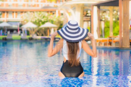 Téléchargez les photos : Beau portrait jeune femme asiatique sourire heureux se détendre autour de la piscine en hôtel resort pour les loisirs - en image libre de droit