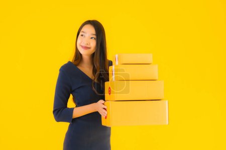 Photo for Portrait beautiful young asian woman with cardboard box packkage ready for shipping on yellow isolated background - Royalty Free Image