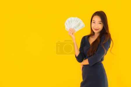 Téléchargez les photos : Portrait belle jeune femme asiatique avec de l'argent et de l'argent sur fond jaune isolé - en image libre de droit