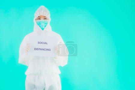 Photo for Portrait beautiful young asian doctor woman wear ppe or  personal protective equipment for protect from coronavirus or covid19 with social distacing sign on blue isolated background - Royalty Free Image