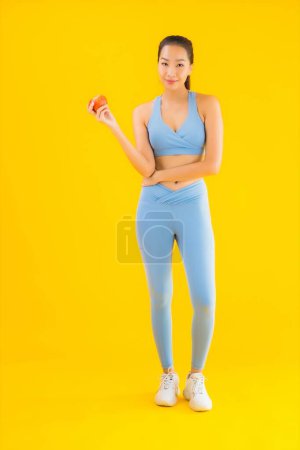 Téléchargez les photos : Portrait belle jeune femme asiatique porter des vêtements de sport prêt à l'exercice avec des fruits de pomme fond isolé - en image libre de droit