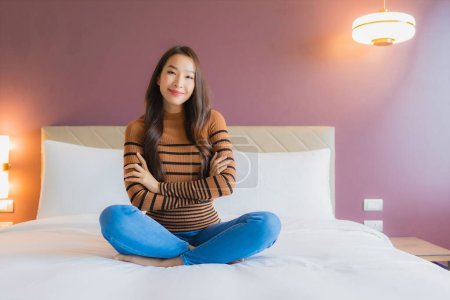 Téléchargez les photos : Portrait belle jeune femme asiatique sourire se détendre sur le lit dans la chambre intérieur - en image libre de droit