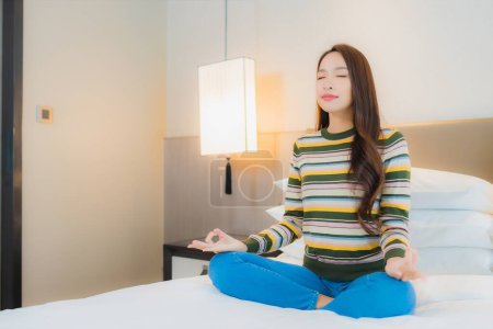 Téléchargez les photos : Portrait belle jeune femme asiatique méditation sur le lit dans la chambre intérieur - en image libre de droit