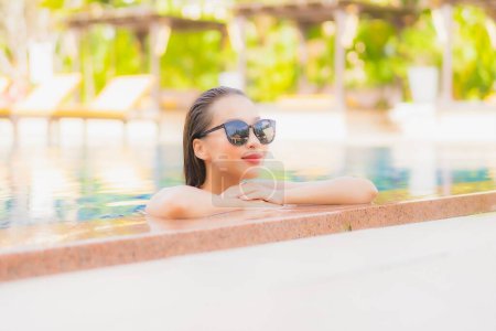 Téléchargez les photos : Portrait belle jeune femme asiatique relax sourire loisirs autour de la piscine extérieure dans la station hôtelière en voyage de vacances - en image libre de droit