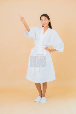 Téléchargez les photos : Portrait belle jeune femme asiatique porter peignoir avec sourire sur fond de couleur - en image libre de droit
