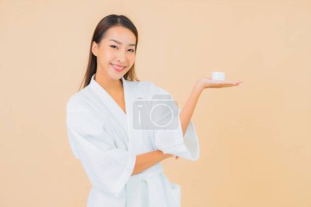 Téléchargez les photos : Portrait belle jeune femme asiatique avec lotion bouteille et crème visage sur fond isolé couleur - en image libre de droit