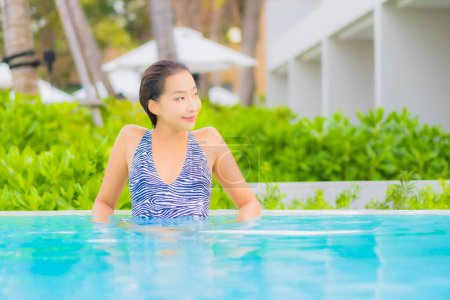 Foto de Retrato hermosa joven mujer asiática relajarse ocio alrededor de piscina al aire libre con mar océano playa - Imagen libre de derechos