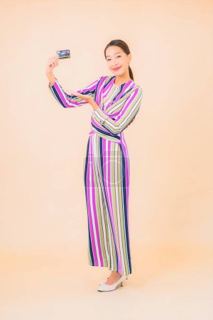 Foto de Retrato hermosa joven asiática mujer con teléfono móvil inteligente y tarjeta de crédito en color aislado fondo - Imagen libre de derechos