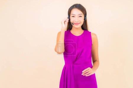 Foto de Retrato hermosa joven asiática mujer con auriculares para call center cliente en color de fondo - Imagen libre de derechos