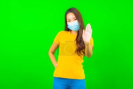 Photo for Portrait beautiful young asian woman wear mask for protect from covid19 or coronavirus on green isolated background - Royalty Free Image