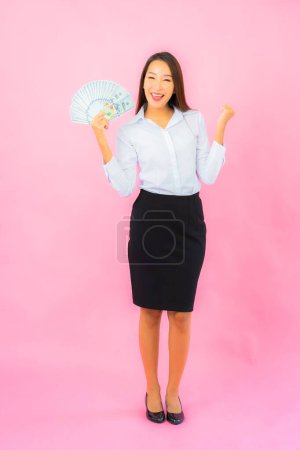 Foto de Retrato hermosa joven asiática mujer con un montón de dinero en efectivo y dinero en rosa fondo - Imagen libre de derechos