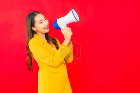 Téléchargez les photos : Portrait belle jeune femme d'affaires asiatique avec mégaphone pour la communication sur fond rouge - en image libre de droit