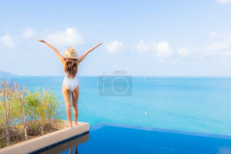 Téléchargez les photos : Portrait belle jeune femme asiatique relax sourire loisirs autour de la piscine extérieure avec océan de mer en vacances Voyage - en image libre de droit