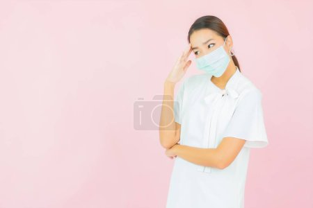 Foto de Retrato hermosa joven mujer asiática usar máscara para proteger covid19 sobre fondo rosa - Imagen libre de derechos