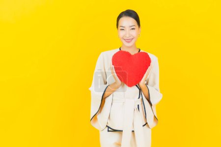Photo for Portrait beautiful young business asian woman with heart pillow shape on yellow color background - Royalty Free Image